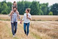 Young Caucasian family walking across field with young girl holding bouquet of flowers, concept organic ecologically friendly fami