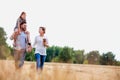 Young Caucasian family walking across field with young child on her fathers shoulders with the wife holding a bouquet of flowers