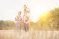 Young Caucasian family walking across field with young child on her fathers shoulders with the wife holding a bouquet of flowers