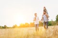 Young Caucasian family walking across field with young child on her fathers shoulders with the wife holding a bouquet of flowers