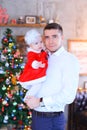 Young caucasian father keeping little daughter near Christmas tree in background.