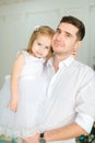 Young caucasian father keeping little daughter wearing white dress.