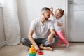 Young Caucasian father playing with child girl. Male man parent entertains toddler daughter sitting at home. Authentic lifestyle