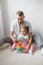 Young Caucasian father playing toys with child girl. Male man parent entertains toddler daughter sitting at home.