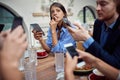 Young caucasian female absent in thoughts on unsocial lunch in restaurant, where each person using cell phone and not talking to