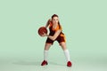 Young caucasian female basketball player against mint colored studio background