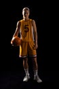 Young Caucasian female basketball player in basketball attire poses confidently on a black backgroun Royalty Free Stock Photo