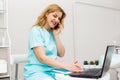 Young caucasian female doctor using mobile phone talking while sitting in hospital office. happy woman medical worker having Royalty Free Stock Photo