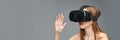 Young caucasian female engaged with virtual reality headset on gray background Royalty Free Stock Photo