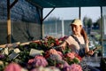 young caucasian female gardene writing in notebook in greenhouse, sit next to flowers Royalty Free Stock Photo