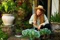 Young caucasian female gardener planting vegetables smiling happily. Junior cheerful woman with trowel sitting in her