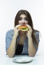 Young Caucasian Female with Hamburger and Empty Plate in Studio. Posing in Striped Shirt Indoors