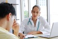 Young Caucasian Female psychiatrist is specialist in psychiatry is talking with asian male Patient and searching results on laptop Royalty Free Stock Photo