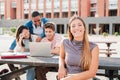 Young caucasian female student, smiling and looking at camera sitting with her classmates at university campus. Blonde Royalty Free Stock Photo