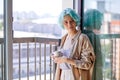 young caucasian female with unusual coloured blue hair on near window with mug