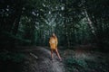 Young, Caucasian female wearing a yellow hoodie in a forest in Poland.