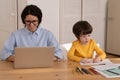 Young caucasian female work on laptop as son draws. Remote home office at covid-19 lockdown concept Royalty Free Stock Photo