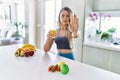 Young caucasian fitness woman wearing sportswear drinking healthy orange juice with open hand doing stop sign with serious and Royalty Free Stock Photo