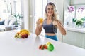Young caucasian fitness woman wearing sportswear drinking healthy orange juice pointing finger to one self smiling happy and proud Royalty Free Stock Photo
