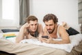 Gays lying on bed with smartphone Royalty Free Stock Photo
