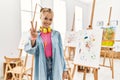 Young caucasian girl at art studio showing and pointing up with fingers number two while smiling confident and happy Royalty Free Stock Photo