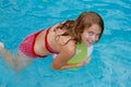 Smling girl holding a beach ball in a swimming pool Royalty Free Stock Photo