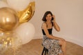 Young caucasian girl laughs heartily while sitting in spacious room with balloons in foreground. Royalty Free Stock Photo