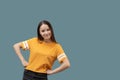 Young caucasian girl with long brown hair smiles, has fun, happy, holds hands on a belt, isolated on gray background