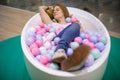 young caucasian girl is lying in the bath with multi-colored plastic balls and smiling with closed eyes. close-up, soft focus Royalty Free Stock Photo