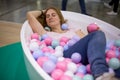 Young caucasian girl is lying in the bath with multi-colored plastic balls and smiling with closed eyes. close-up, soft Royalty Free Stock Photo