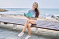 Young caucasian girl reading book sitting on the bench at the beach Royalty Free Stock Photo