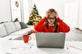 Young caucasian girl sitting on the table working using laptop by christmas tree suffering from headache desperate and stressed Royalty Free Stock Photo