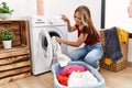 Young caucasian girl smiling happy cleaning clothes using whasing machine at home Royalty Free Stock Photo