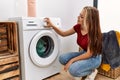 Young caucasian girl smiling happy cleaning clothes using whasing machine at home Royalty Free Stock Photo