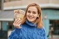 Young caucasian girl smiling happy holding hungarian forint banknotes at the city