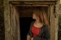 Young Caucasian girl standing in front of an old wooden door of an abandoned house Royalty Free Stock Photo