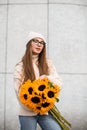 Young caucasian girl stands against the background of white wall and holds bouquet of sunflowers in her hands Royalty Free Stock Photo