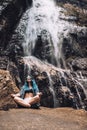 Young Caucasian girl under Diyaluma waterfall, Sri Lanka. Happy woman in meditation pose on vacation. Wellness lifestyle, healthy