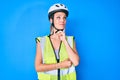 Young caucasian girl wearing bike helmet and reflective vest serious face thinking about question with hand on chin, thoughtful