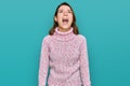 Young caucasian girl wearing wool winter sweater angry and mad screaming frustrated and furious, shouting with anger Royalty Free Stock Photo
