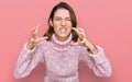 Young caucasian girl wearing wool winter sweater shouting frustrated with rage, hands trying to strangle, yelling mad Royalty Free Stock Photo