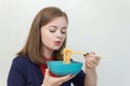 Young caucasian girl woman eating instant noodles ramen with chopsticks Royalty Free Stock Photo