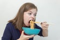 Young caucasian girl woman eating instant noodles ramen with chopsticks Royalty Free Stock Photo