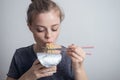 Young caucasian girl woman eating instant noodles ramen with chopsticks Royalty Free Stock Photo