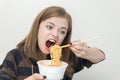 Young caucasian girl woman eating instant noodles ramen with chopsticks Royalty Free Stock Photo