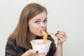 Young caucasian girl woman eating instant noodles ramen with chopsticks Royalty Free Stock Photo