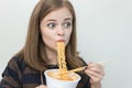 Young caucasian girl woman eating instant noodles ramen with chopsticks Royalty Free Stock Photo