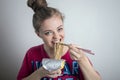 Young caucasian girl woman eating instant noodles ramen with chopsticks Royalty Free Stock Photo