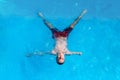 Young guy with an amputated arm is swimming in a pool like a star, top view