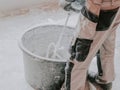 A young caucasian guy a plasterer holds a construction electric mixer and stirs dry putty with water Royalty Free Stock Photo